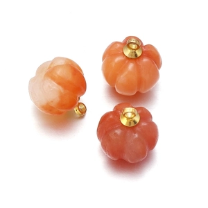 Three pumpkin-shaped orange aventurine agate pendants with golden rings on white background