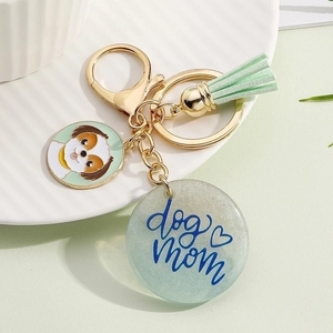 Close-up of dog mom resin pendant with a light green tassel and golden keychain
