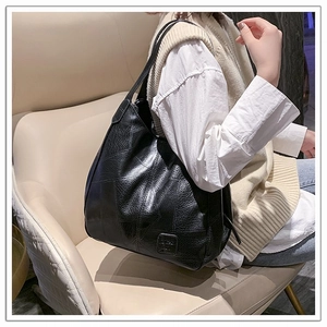 Detail of black faux leather tote bag showing litchi texture and geometric stitching