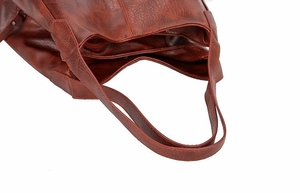 Close-up of red-brown faux leather tote bag showing detailed stitching and pebble texture