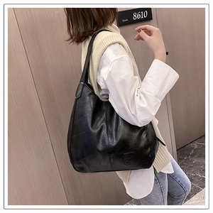 Detail of black large capacity hobo bag with pebbled leather texture and embossed logo