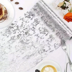 Macro detail of white mesh table runner with irregular shimmering silver foil patterns
