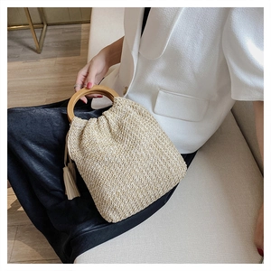 Detail of hand-woven straw bag with round wooden handle and stylish side tassel accessory