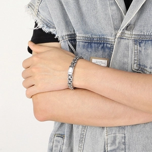 Detail of a bold silver stainless steel curb chain bracelet worn on a male wrist