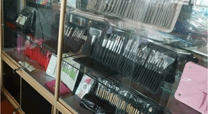 Various makeup brush sets displayed in colorful cases within a glass showcase cabinet
