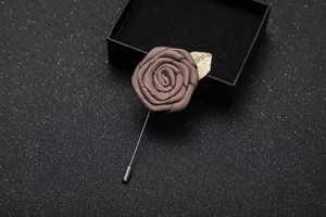 Detailed view of handmade dark grey fabric rose brooch with golden leaf on metal pin