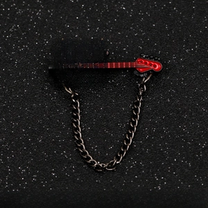 Macro shot of a red electric guitar brooch with black strings and metallic hanging chain