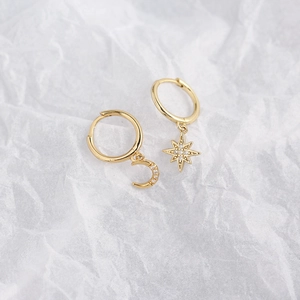 Detail of asymmetric gold moon and star earrings with sparkling zircon inlay