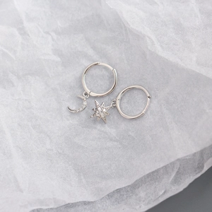 Macro detail of silver S925 asymmetric moon and star earrings with pavé crystals