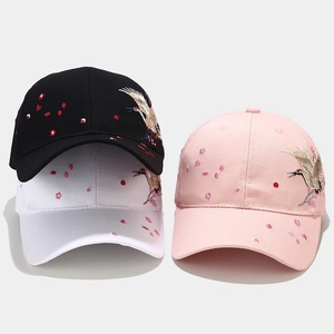 Close-up of crane and cherry blossom embroidery on cotton baseball caps in three colors