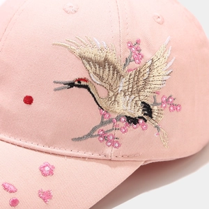 Detail of high-density crane and cherry blossom embroidery on pink cotton baseball cap
