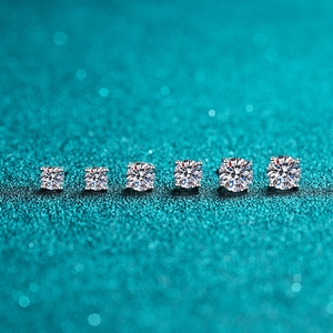 Detailed view of six silver four-prong stud earrings in graduated sizes on teal surface