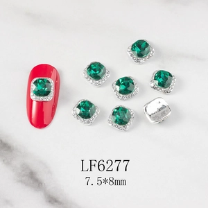 Close-up of emerald square nail rhinestones with white crystal border on red nail