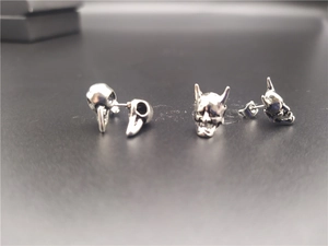 Macro shot of vintage silver punk bird skull and hannya mask stud earrings set
