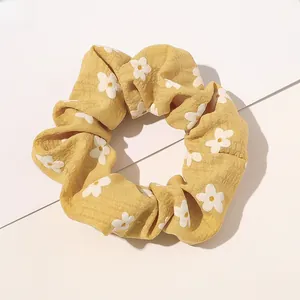 Close-up of yellow floral plaid scrunchie with soft fabric texture and elastic band