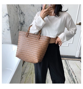 Détail d'un cabas en cuir tressé marron avec une poignée en bambou vintage et métal doré