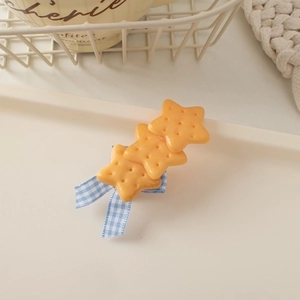 Detail of star-shaped cookie hair clips with blue gingham bow on cream tray
