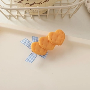 Detail showing heart-shaped biscuit hair clips with blue checkered ribbon on a tray