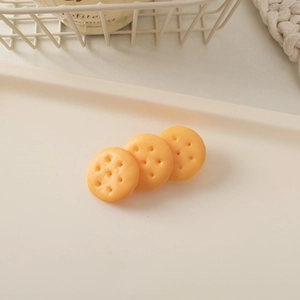 Detailed view of three resin biscuit-shaped hair charms on a cream decorative tray