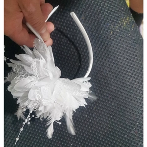 Detail shot of white feather fascinator with mesh flower and pearl beads on headband