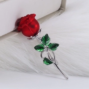 Elegant red enamel rose brooch with green leaves on white plush background