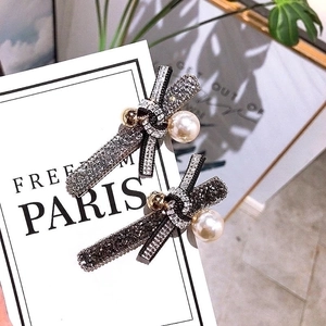 Elegant rhinestone bow hair clip with a large pearl accent on a 45-degree angle