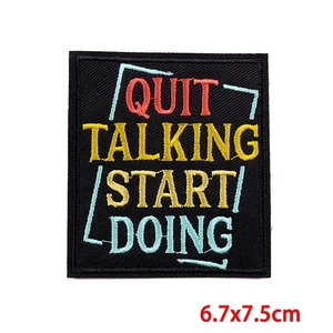 Macro detail of 'QUIT TALKING START DOING' embroidered patch with precise black border