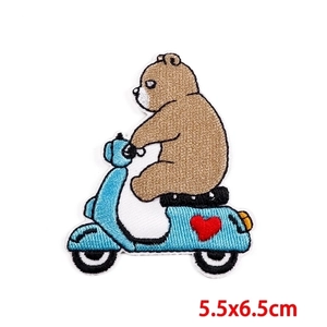 Detail of embroidered brown bear on a light blue scooter with a red heart patch