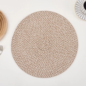 Detail of round woven placemat showing two-tone brown and white texture on white table