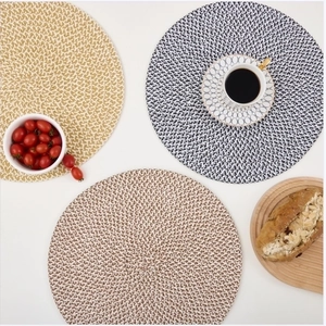 Three circular woven placemats in beige and mixed grey tones on a white background