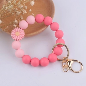 Detail of pink silicone beaded wristlet with daisy charm and gold lobster clasp