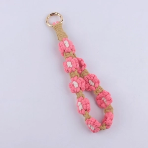 Detail of handmade woven cotton daisy keychain with pink flower pattern and gold ring