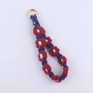 Detail of handmade woven cotton daisy lanyard with navy blue and red patterns and gold ring