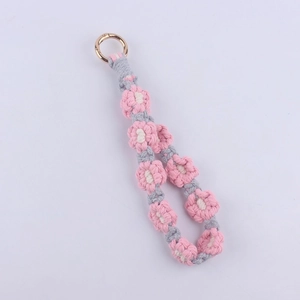 Macro view of hand-woven daisy floral keychain with pink cotton cord and gold spring ring