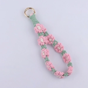 Macro detail of handmade woven floral keychain with pink daisies and golden spring ring
