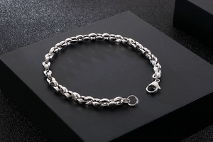 Detail eines silbernen Gliederkettenarmbands mit Karabinerverschluss auf schwarzem Display