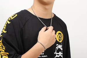 Detail der silbernen Schweinenasen-Kette und des Armbands auf einem schwarzen T-Shirt
