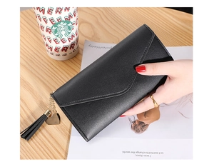 Macro detail of black litchi texture on long envelope wallet with heart tassel