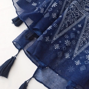 Detailed close-up of blue paisley patterns and fringe edges on cotton linen scarf