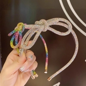 Rainbow rhinestone headband with an asymmetrical bow design on a thin metal band