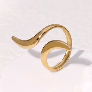 Detailed view of a gold-tone minimalist wave design ring on a white stone background