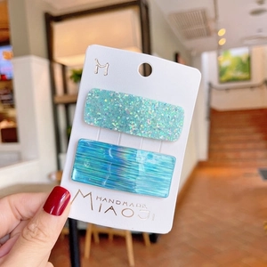 Set of two rectangular blue laser glitter hair clips on a white brand card display