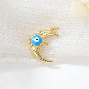 Gold moon pendant with blue evil eye and radiant texture on white fabric background