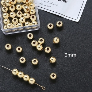 Detalle de cuentas espaciadoras redondas bañadas en oro de 6mm con caja transparente
