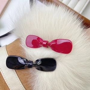 Glossy bow hair clips in red and black colors on a soft fur surface display