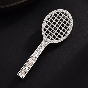 Macro detail of tennis racket brooch featuring sparkling rhinestones on textured background
