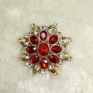 Macro view of gold star brooch featuring red gemstones and white crystals on white fur