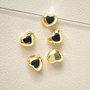 Macro detail of 18k gold plated heart spacer beads with black inlay for DIY jewelry