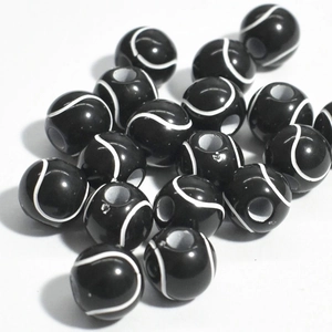 Close-up of black acrylic tennis ball beads with white curved lines for jewelry making