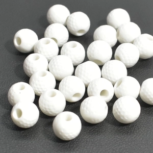 Detailed macro shot of white golf-style acrylic spacer beads on a black textured background